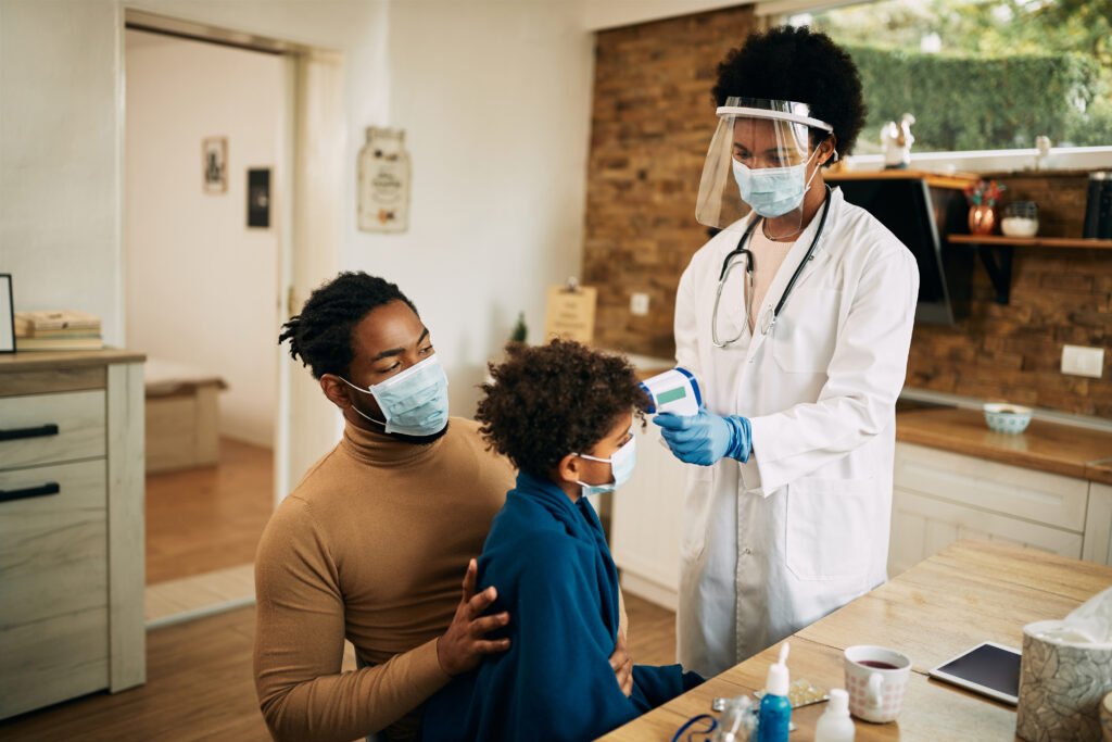 black female pediatrician measuring boy's temperature during a h